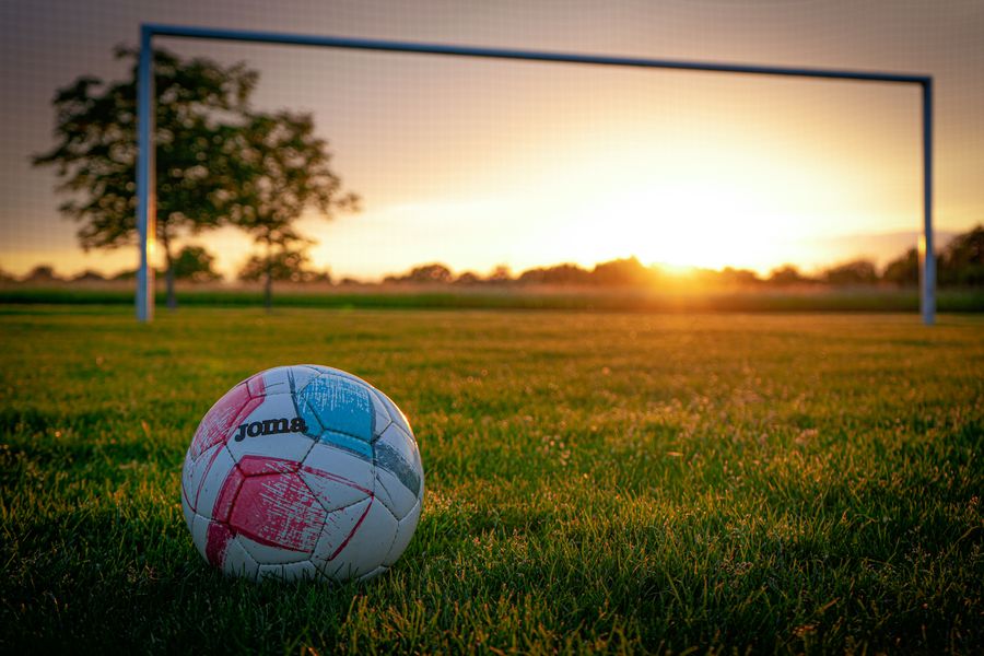 Bola sepak di lapangan saat matahari terbenam, melambangkan awal perjalanan