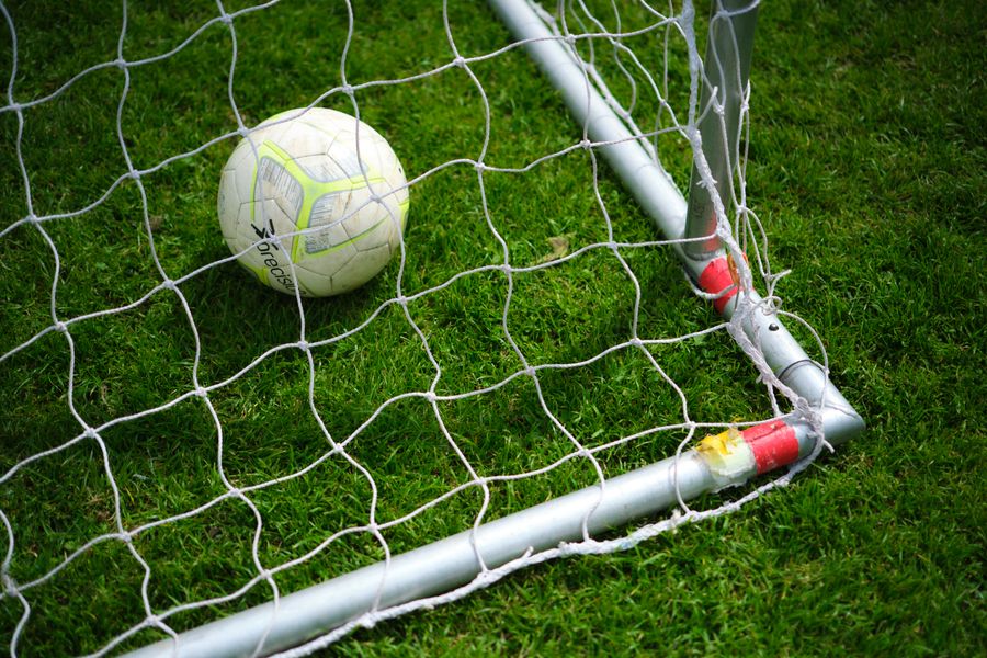Bola sepak berada di dalam jaring gawang di lapangan hijau